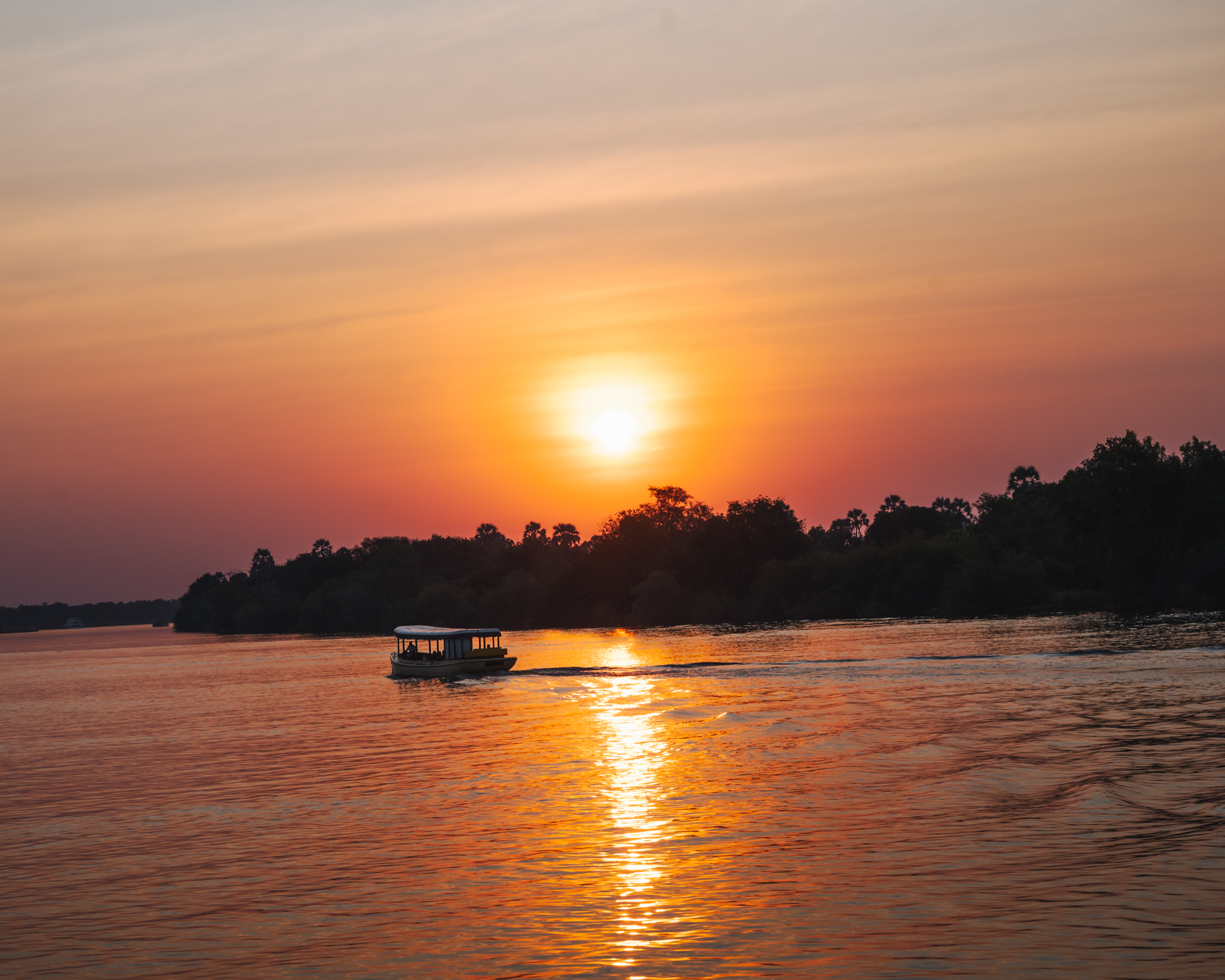 Sailing down the Zambezi River at sunset on a safari river cruise.